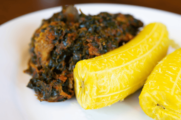 A delicious bowl of Efo Riro and boiled Plantain, a flavorful Nigerian spinach stew with tomatoes, peppers, and spices.