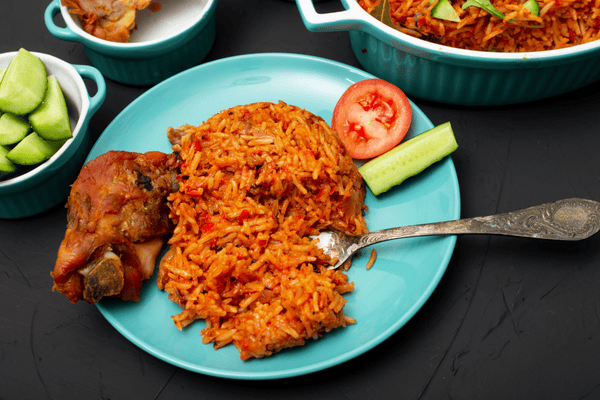 A delicious plate of Jollof rice served with succulent grilled chicken, garnished with fresh vegetables, showcasing a classic West African dish.